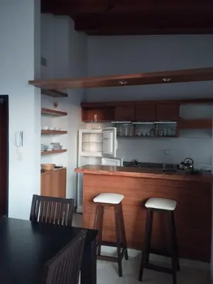 a kitchen with a counter and two stools in it at Paraíso Serrano 18 in Villa Ciudad Parque