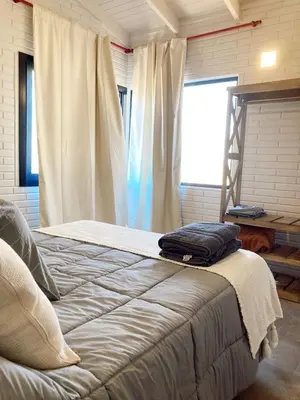 a bed sitting in a room with a window at Cabañas Amapolas Los Reartes in Los Reartes