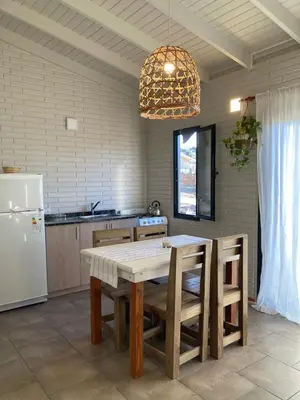 a kitchen with a table and a white refrigerator at Cabañas Amapolas Los Reartes in Los Reartes