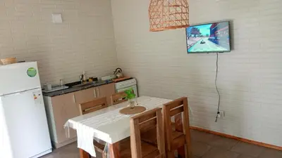 a kitchen with a table and a tv on the wall at Cabañas Amapolas Los Reartes in Los Reartes