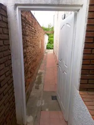 an alley with an open door and a brick wall at Urquiza - Habitación para turistas in Cordoba