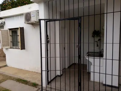 an iron gate in front of a white house at Urquiza - Habitación para turistas in Cordoba