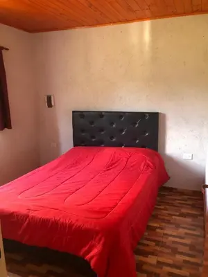 a bedroom with a red bed with a black headboard at Genesis Paz y Montaña Mallin Tanti in Tanti