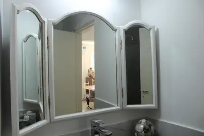 a bathroom with three mirrors above a sink at Reina Paz in Cordoba