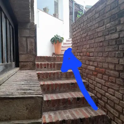 a blue arrow on the stairs of a brick building at Reina Paz in Cordoba