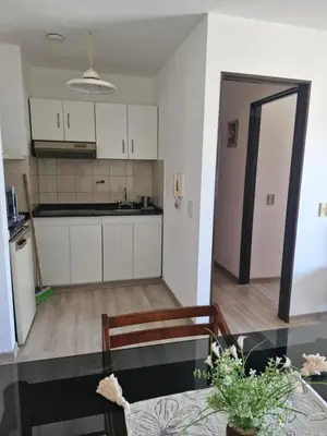 a kitchen with white cabinets and a dining table at Departamento Acuario II - a metros del shopping woo in Villa Carlos Paz