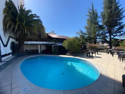 a large blue swimming pool next to a house at Hotel Carlos Paz Centro - MONTECATINI in Villa Carlos Paz
