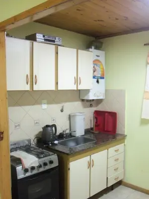 a kitchen with white cabinets and a stove top oven at Cabaña NANO in Tanti