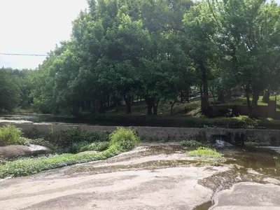 a river with trees and a retaining wall next to a field at Cabaña NANO in Tanti