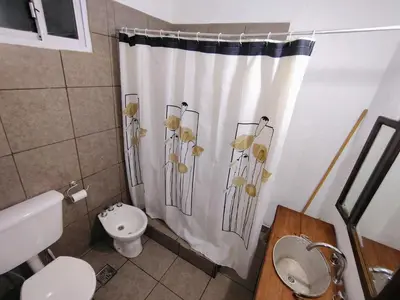 a bathroom with a shower curtain with flowers on it at Refugio del Rio in Los Reartes