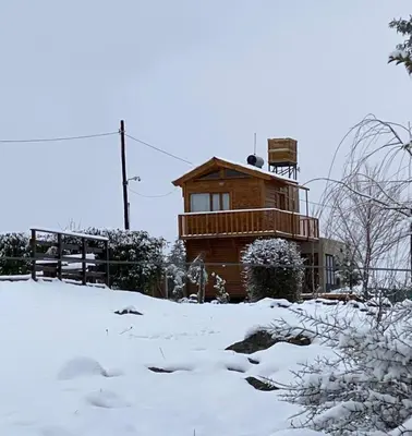 a house covered in snow in front of a house at Cabaña Snowflakes in Villa Yacanto
