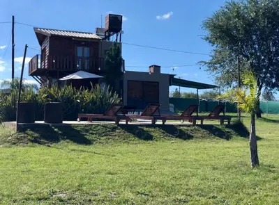 a house with benches in front of it at Cabaña Snowflakes in Villa Yacanto