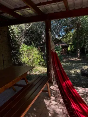 a hammock on a porch with a picnic table at Cabañas Los Horneros in Santa Rosa de Calamuchita