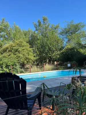 a swimming pool with two chairs in front of it at Cabañas Los Horneros in Santa Rosa de Calamuchita