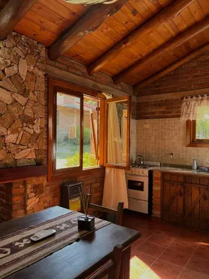 a kitchen with wooden walls and a wooden table at Cabañas Los Horneros in Santa Rosa de Calamuchita