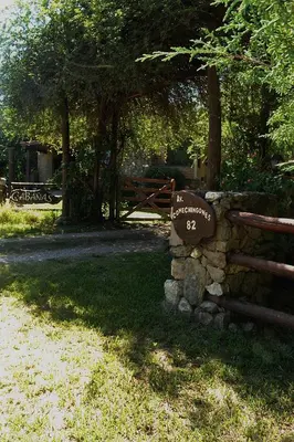 a sign on a stone wall next to a fence at Cabañas Los Horneros in Santa Rosa de Calamuchita