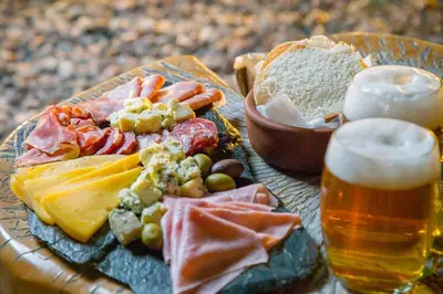 a table with a plate of food and a glass of beer at Ayres del Champaqui Hotel Boutique Experiencial & Spa in Villa General Belgrano