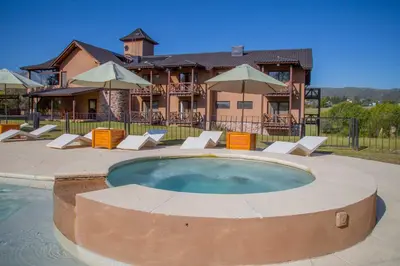 a house with a swimming pool in front of a house at Ayres del Champaqui Hotel Boutique Experiencial & Spa in Villa General Belgrano