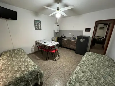 a room with two beds and a table and a kitchen at Cybeles Family Apart in Villa Carlos Paz