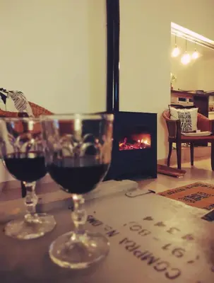 two glasses of wine sitting on a table with a fireplace at Mauro y Sonia in Estancia Vieja