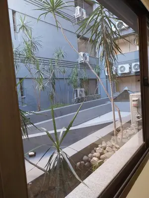 a window with a view of a pool and palm trees at Departamento NYC 4 Premium - Edificio VILAUT by INMOVE Temporarios in Cordoba