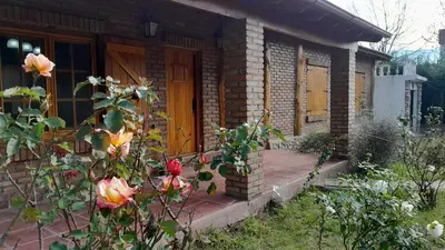 a brick house with a wooden door and flowers at Casa de campo in Los Hornillos