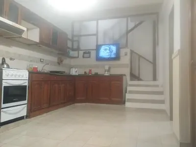 a kitchen with wooden cabinets and a tv on the wall at Lo de Claudia in Alta Gracia