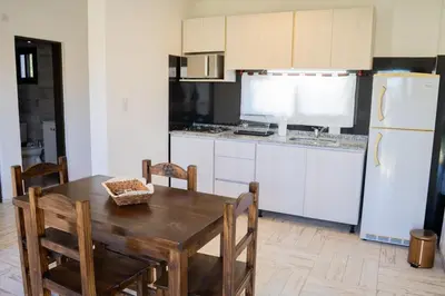 a kitchen with a wooden table and a white refrigerator at Complejo Malucos in Pantanillo