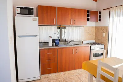 a kitchen with wooden cabinets and a white refrigerator at Complejo Malucos in Pantanillo