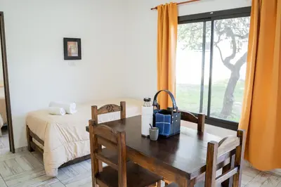 a room with a table and a bed and a window at Complejo Malucos in Pantanillo