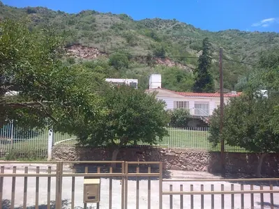 a house with a fence in front of a mountain at Mágico atardecer in Villa Carlos Paz