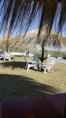 a group of lawn chairs sitting under a straw umbrella at Howard Johnson Hotel Piedras Moras in Almafuerte