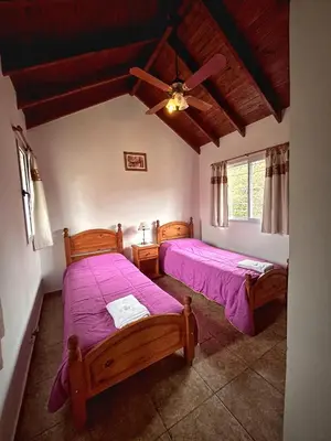 a bedroom with two beds and a ceiling fan at Cabañas Abril in Merlo