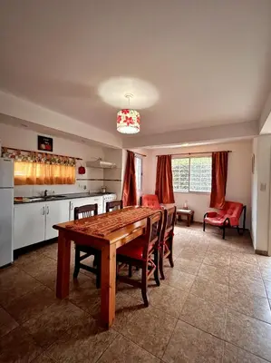 a kitchen with a wooden table and red chairs at Cabañas Abril in Merlo