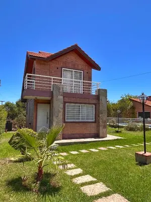 a red brick house with a palm tree in the yard at Cabañas Abril in Merlo