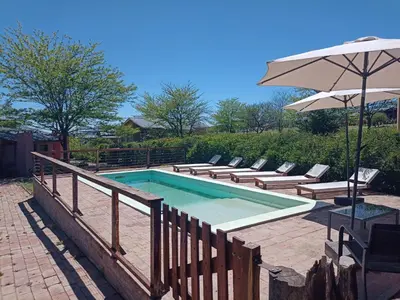a swimming pool with lounge chairs and an umbrella at Cabañas La Ruka in Los Reartes