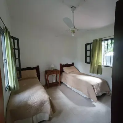 a bedroom with two beds and a table and windows at Excepcional Casa de campo in Villa Anizacate