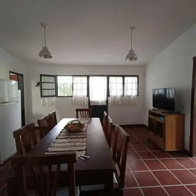 a dining room with a table and chairs and a television at Excepcional Casa de campo in Villa Anizacate