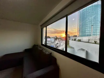 a room with a couch and a large window with a sunset at FTE HOTEL QUINTO CENTENARIO NUEVOCENTRO shopping LUMINOSO DTO EXCELENTE VISTA 1 dor in Cordoba