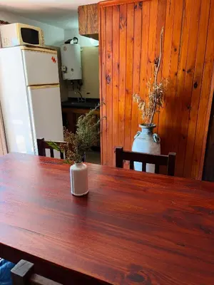 a kitchen with a wooden table and a refrigerator at Departamentos Pasini in Villa Carlos Paz
