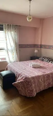 a bedroom with a bed with a pink blanket and a window at Julia Apparts - DEPARTAMENTO EN EL CENTRO DE LA CIUDAD in Cordoba