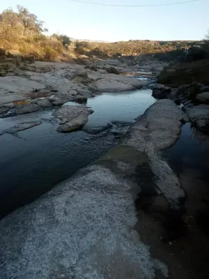an aerial view of a river with rocks at la balsa in Mina Clavero
