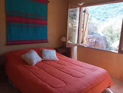 a bedroom with a large red bed with a window at la balsa in Mina Clavero