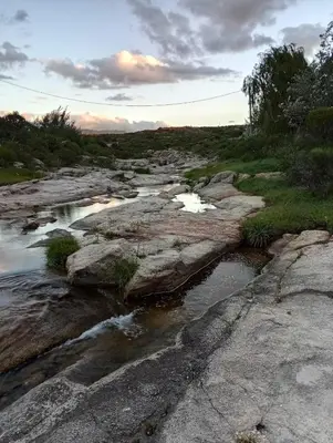 a river with rocks and water in a field at la balsa in Mina Clavero