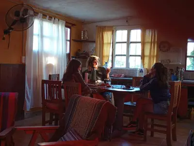 a group of people sitting around a table in a kitchen at la balsa in Mina Clavero