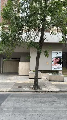 a tree on the side of a building with a poster at Departamento 1 dorm con cochera Nueva Córdoba 1 E INVERHOME INMOBILIARIA in Cordoba
