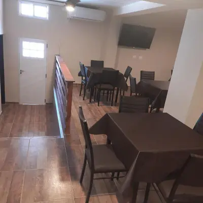a dining room with tables and chairs and a white door at Hospedaje Champaqui in Santa Rosa de Calamuchita