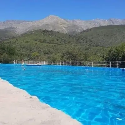 a large blue swimming pool with mountains in the background at Casita en Los Hornillos in Los Hornillos