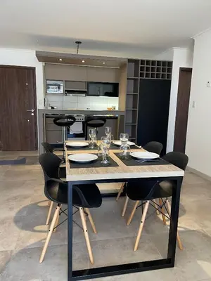 a dining room table with chairs and a kitchen at Depto 