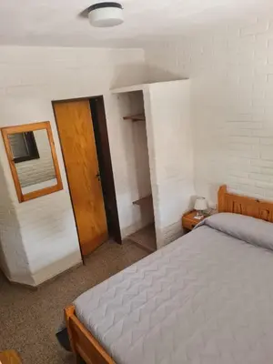 a bedroom with a bed and a mirror and a door at Hostería Los Sauces in Mina Clavero